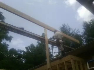 Carpenter setting a ridge beam over a new addition frame in Branchville