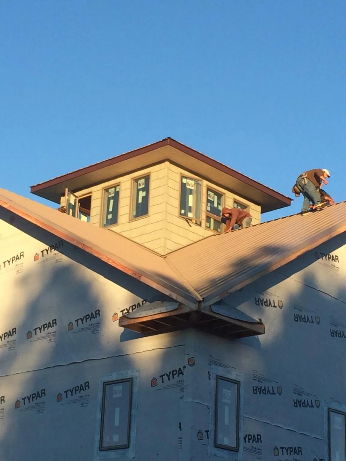 Roofers working around a rooftop cupola on a new metal roof at sunset — Roof Waterproofing in Branchville by Roofing Brothers